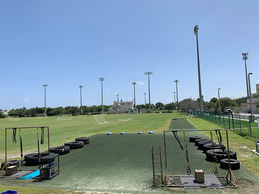 The outdoor training ground: tyres, TRX straps and balance trainers set up along the field.